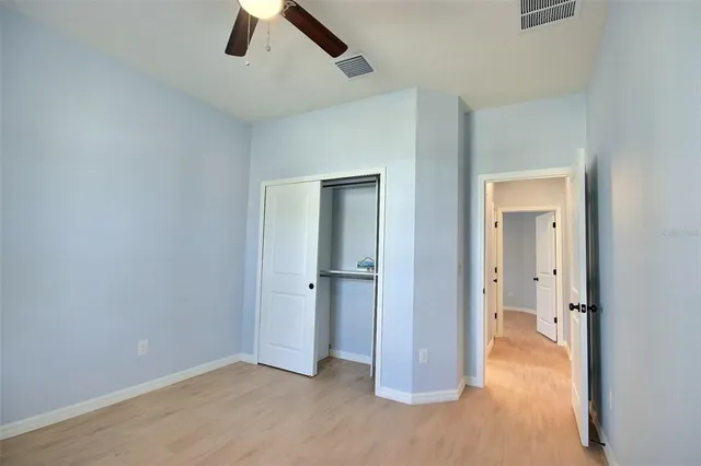 an empty room with closet and a ceiling fan