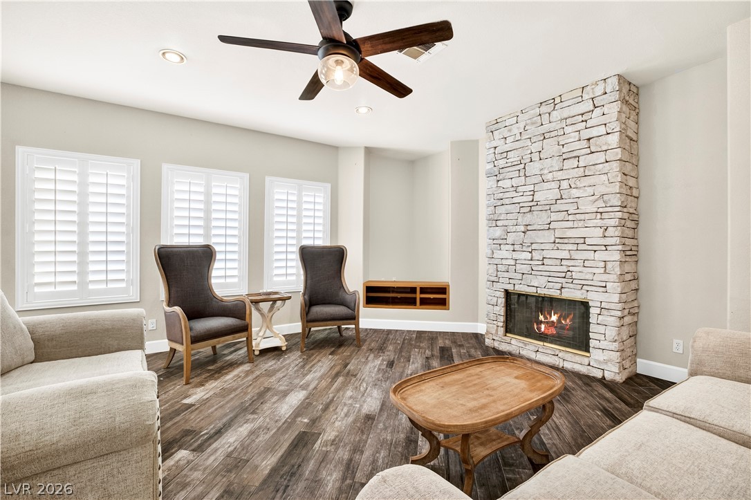 1135 Calico Ridge Drive Henderson, NV 89011 - Photo 17 of 86 An inviting gathering space features a captivating stone fireplace, rich wood-look porcelain tile flooring, and bright windows with plantation shutters.