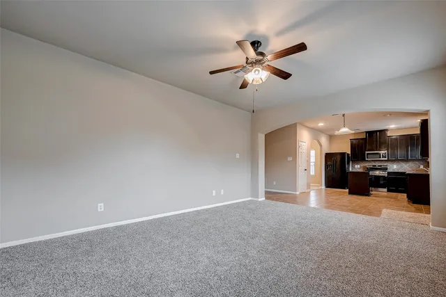 a view of a livingroom with a ceiling fan and a kitchen