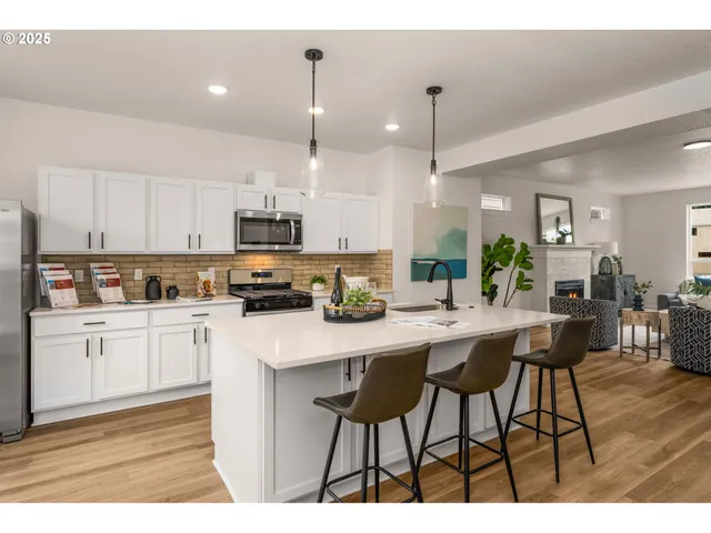 a kitchen with stainless steel appliances kitchen island granite countertop a table chairs sink and cabinets
