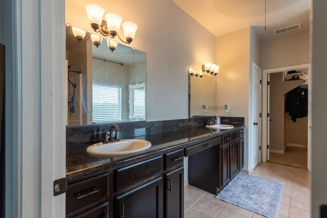a bathroom with a granite countertop sink a mirror and a shower