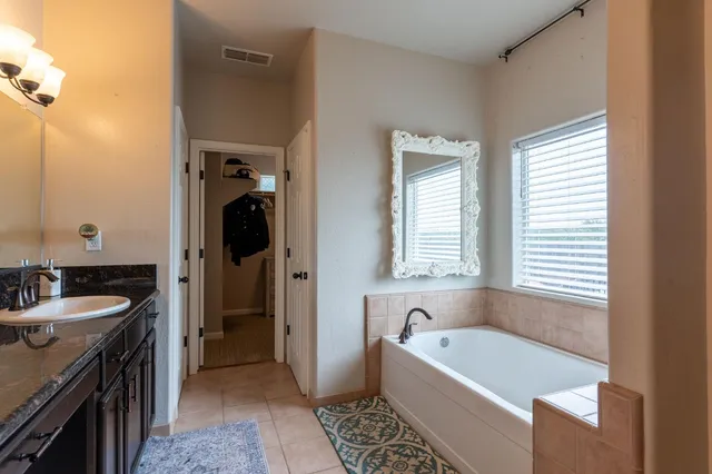 a bathroom with a tub a sink and a large mirror