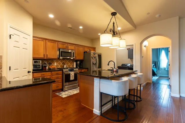 a kitchen with stainless steel appliances a dining table chairs stove refrigerator and microwave