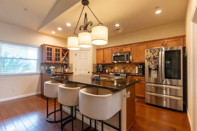 a kitchen with stainless steel appliances granite countertop a sink a stove and refrigerator