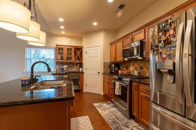 a kitchen with stainless steel appliances granite countertop a refrigerator a stove and a sink