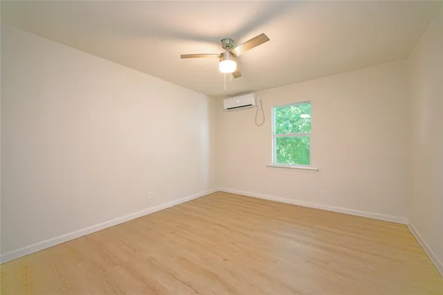 an empty room with a window and a fan