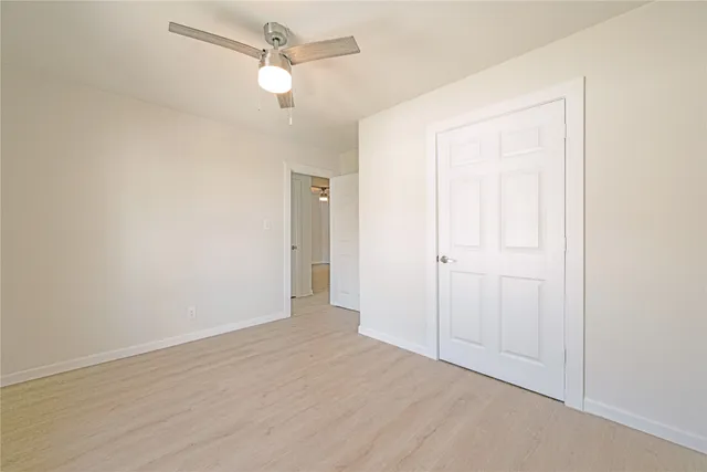 an empty room with closet and a ceiling fan