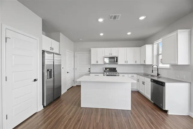 a kitchen with stainless steel appliances granite countertop a white cabinets and wooden floor