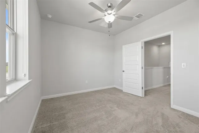 an empty room with a ceiling fan and a window