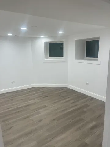 a view of an empty room with wooden floor and windows