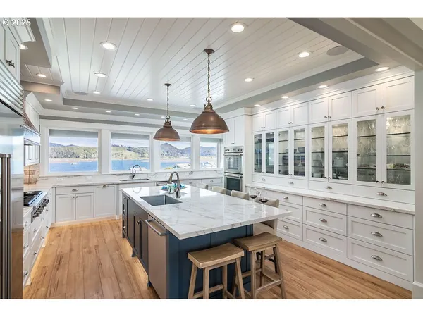 a kitchen with kitchen island granite countertop a stove a sink a dining table and chairs with wooden floor