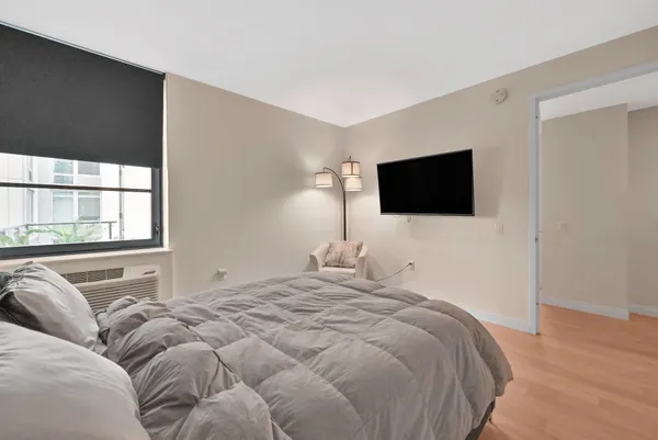 a bedroom with a bed and a flat tv screen on dresser