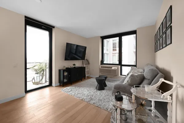 a living room with furniture a flat screen tv and a floor to ceiling window