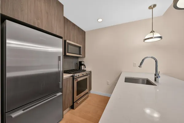 a kitchen with granite countertop stainless steel appliances and wooden floor