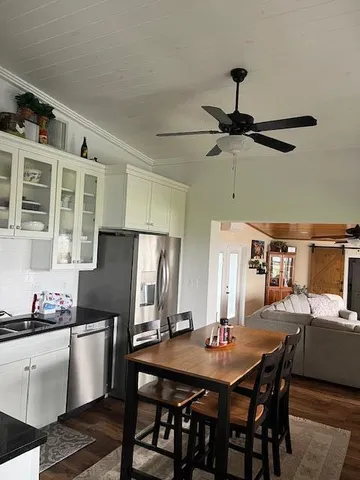 a view of a dining room and kitchen with stainless steel appliances granite countertop a dining table chairs and a refrigerator