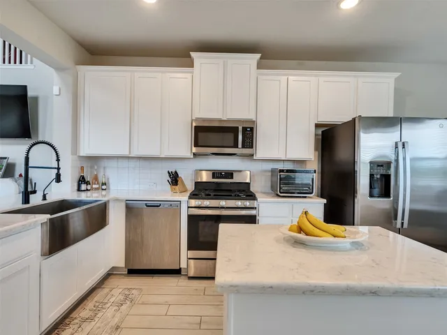a kitchen with stainless steel appliances a stove a sink a microwave and cabinets