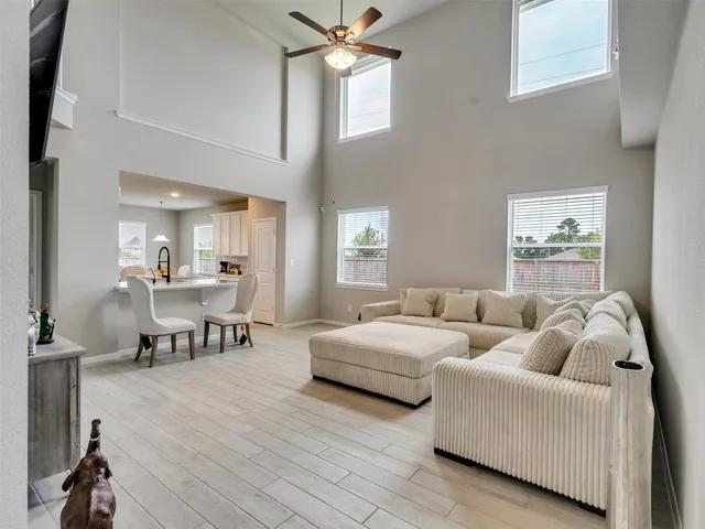 a living room with couches and a dining table with wooden floor