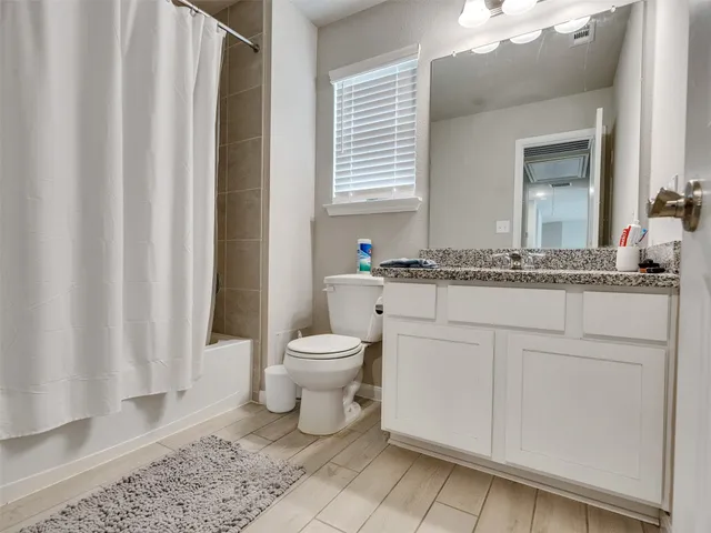 a bathroom with a granite countertop sink toilet and mirror