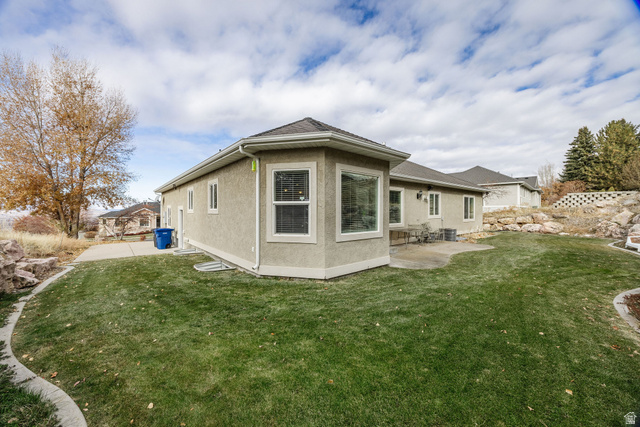 240 Bugle Way Providence, UT 84332 - Photo 5 of 15 Rear exterior featuring a stucco facade, multiple windows with white trim, and a patio area