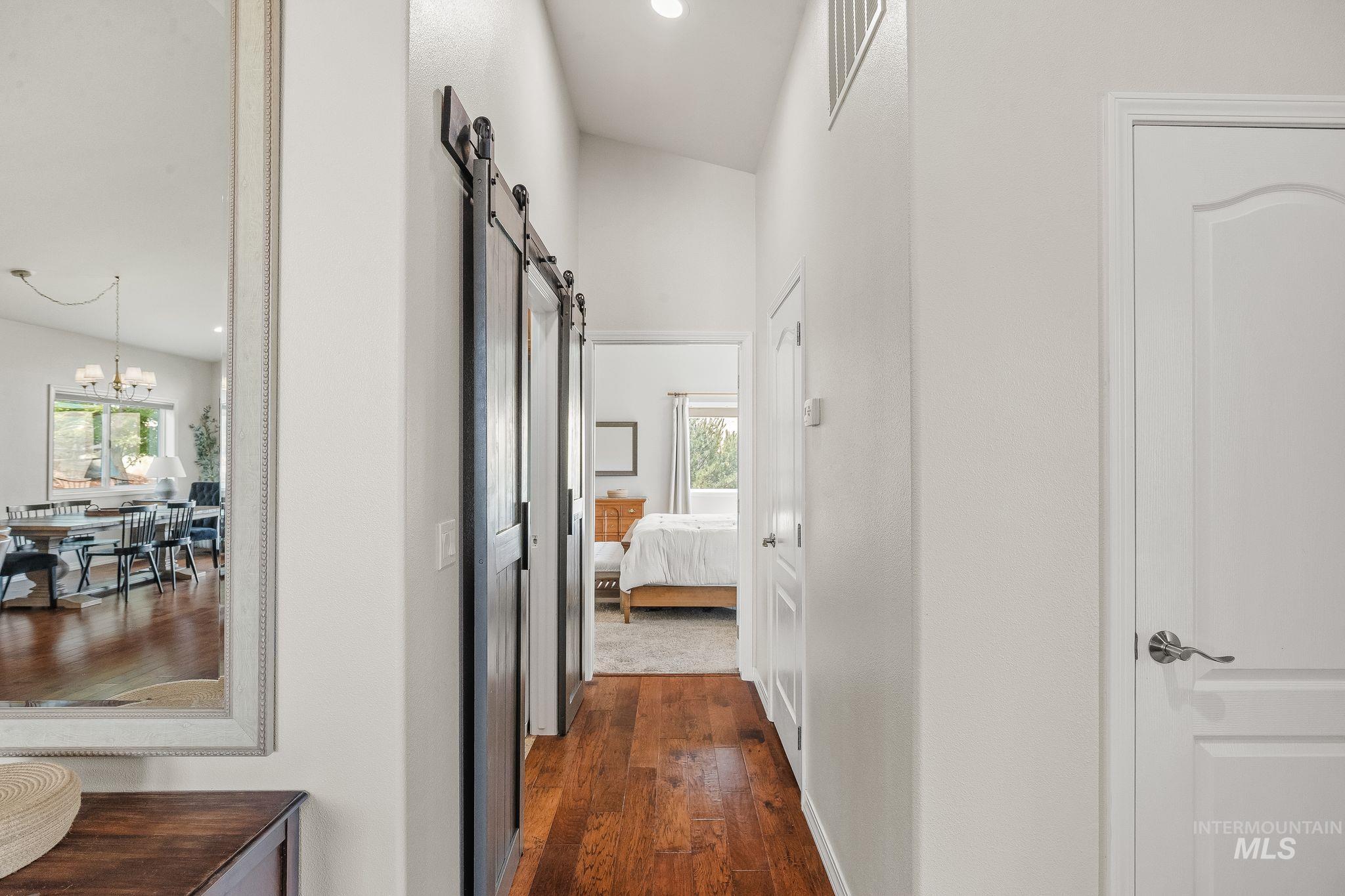 602 Quarry Road Asotin, WA 99402 - Photo 20 of 49 Hallway featuring wood-finish flooring, two barn doors, a vaulted ceiling, and white interior doors