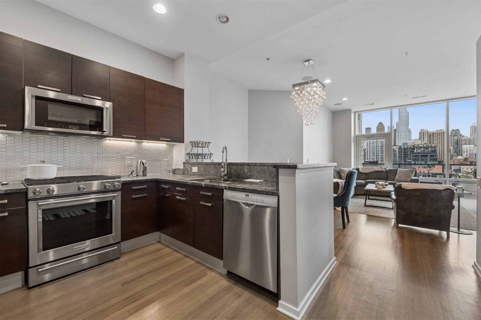 500 West Superior Street, Unit 813 Chicago, IL 60654 - Photo 3 of 18 a kitchen with stainless steel appliances granite countertop a stove top oven a sink dishwasher a dining table and chairs with wooden floor