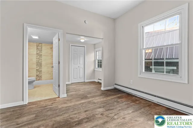 an empty room with wooden floor and windows