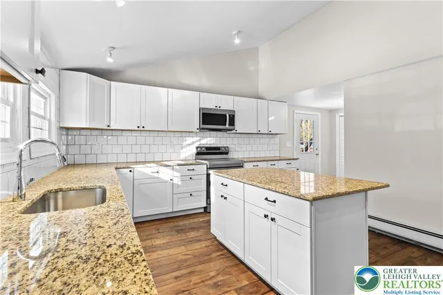 a kitchen with granite countertop a sink a counter top space appliances and cabinets