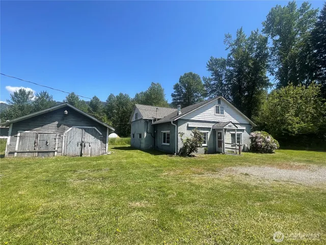 a white house with a big yard and large trees