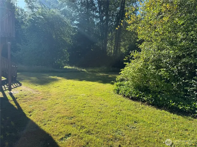 a view of backyard of house with wooden fence