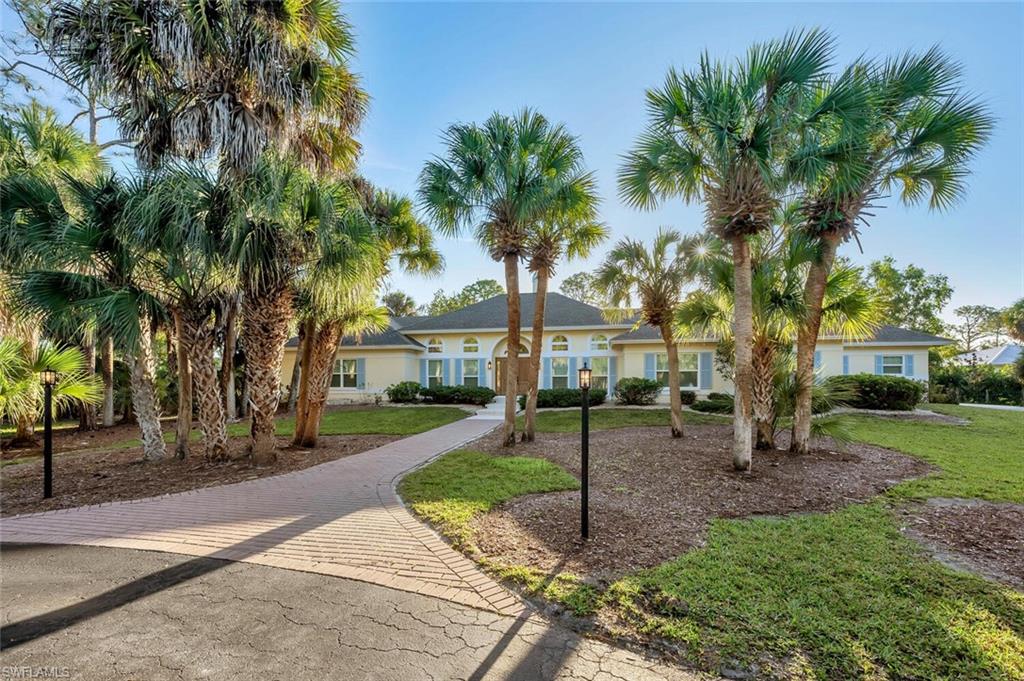 3110 70th Street Southwest Naples, FL 34105 - Photo 5 of 47 a front view of a house with garden and trees