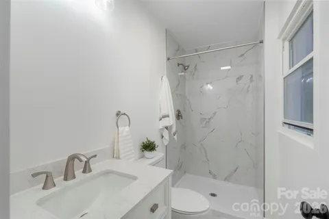 a bathroom with a sink vanity granite toilet and shower