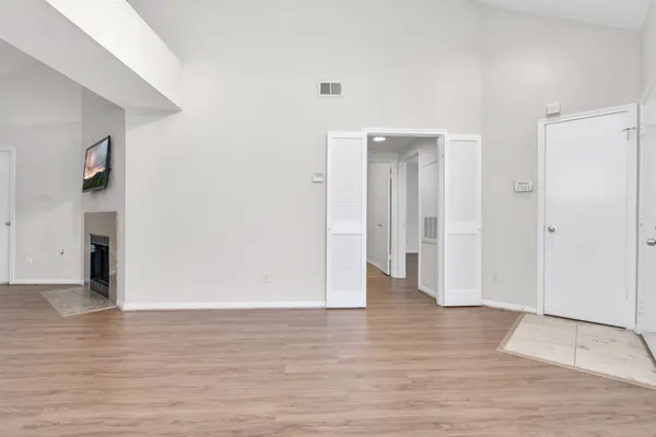 a view of an empty room with wooden floor and a bathroom