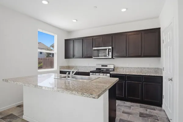 a kitchen with kitchen island granite countertop a sink stove and microwave