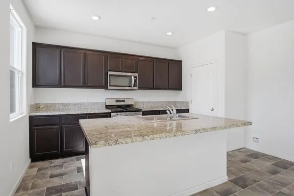 a kitchen with kitchen island granite countertop a stove sink and microwave