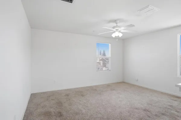an empty room with windows and fan