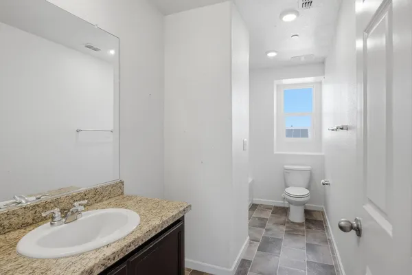 a bathroom with a granite countertop sink a toilet and a mirror