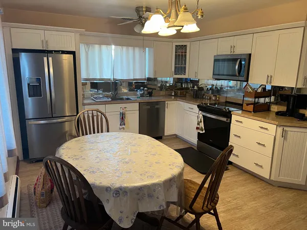 a kitchen with stainless steel appliances granite countertop a refrigerator a stove a sink dishwasher a dining table and chairs with wooden floor