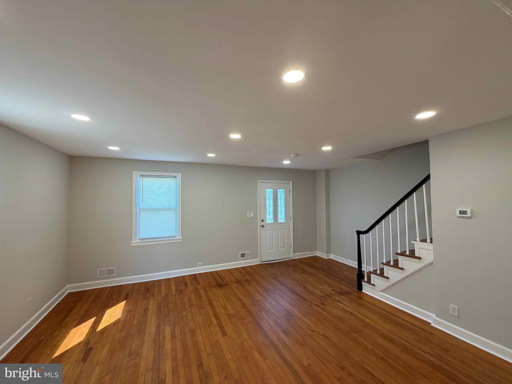 1535 East Cold Spring Lane Baltimore, MD 21218 - Photo 2 of 24 a view of an empty room with wooden floor and window