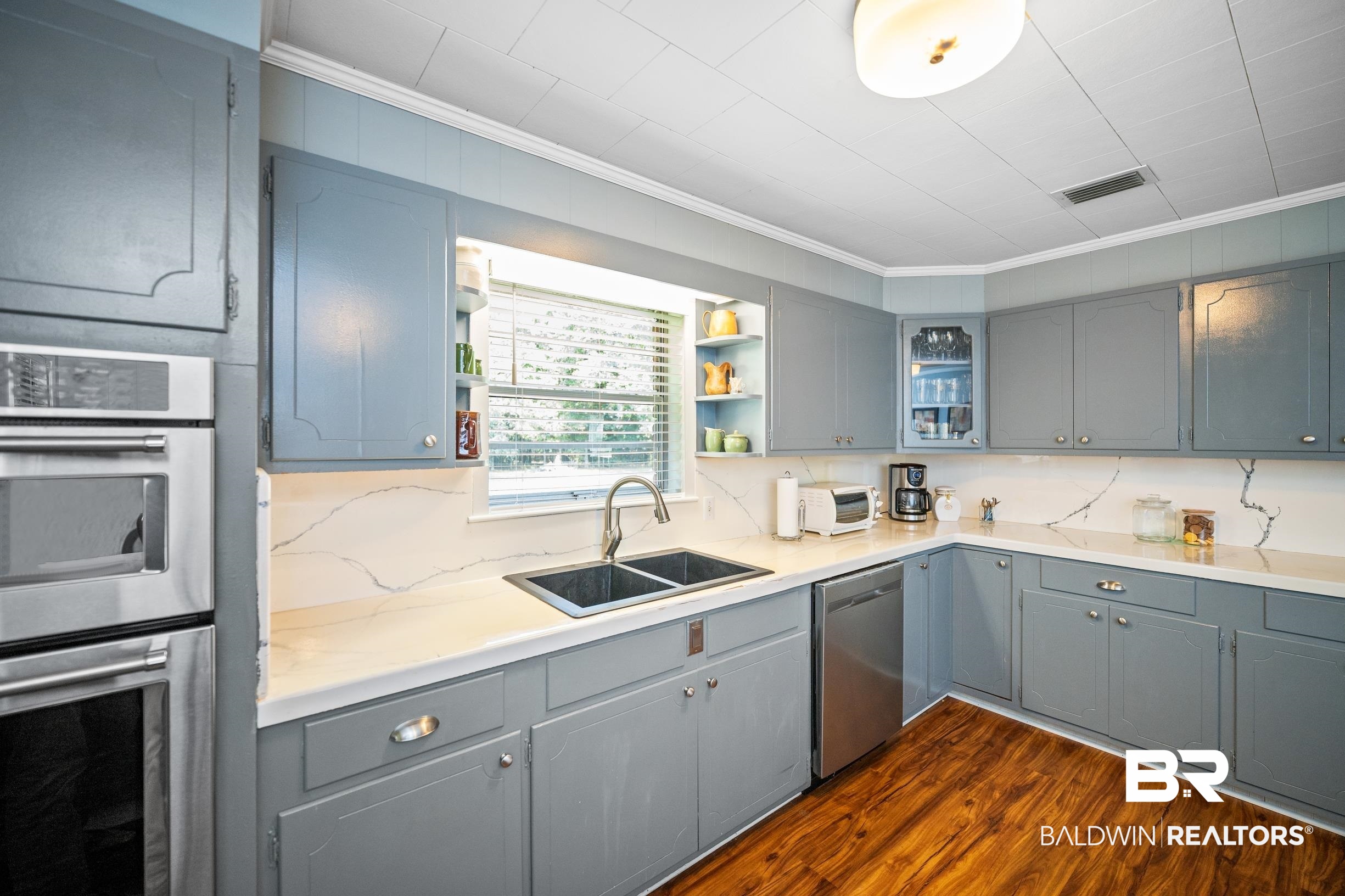 56 Old Bratt Road Atmore, AL 36502 - Photo 12 of 37 Kitchen with appliances with stainless steel finishes, crown molding, gray cabinetry, a sink, and dark wood-style floors
