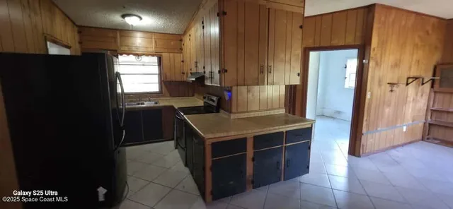 a kitchen with kitchen island granite countertop wooden cabinets and a refrigerator