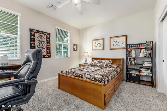 a bedroom with a bed a desk and chair with the bookshelf