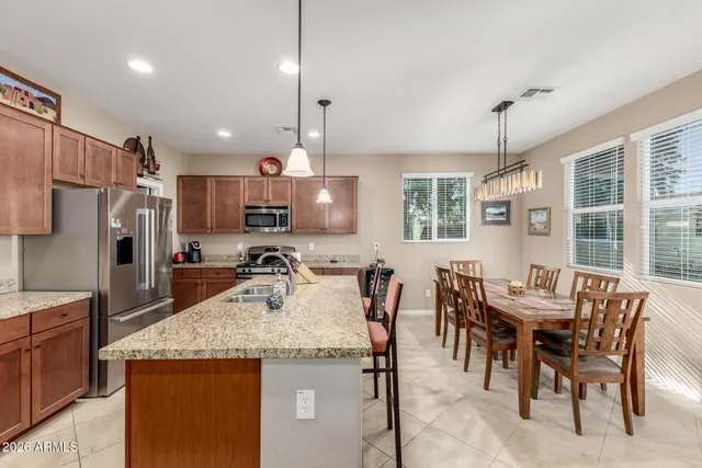 a kitchen with granite countertop kitchen island stainless steel appliances a table a sink and a refrigerator