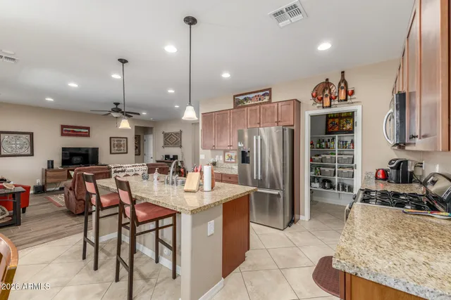 a kitchen with stainless steel appliances kitchen island granite countertop a refrigerator oven a sink a dining table and chairs with wooden floor