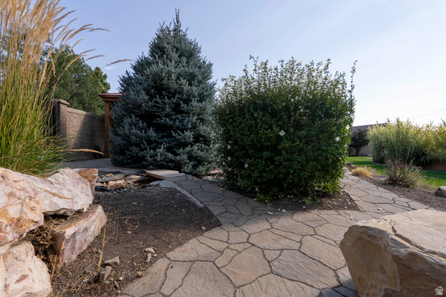 687 South 2080th Street East Springville, UT 84663 - Photo 103 of 149 Landscaped exterior featuring natural stone hardscaping, a mature evergreen tree, and a decorative block wall