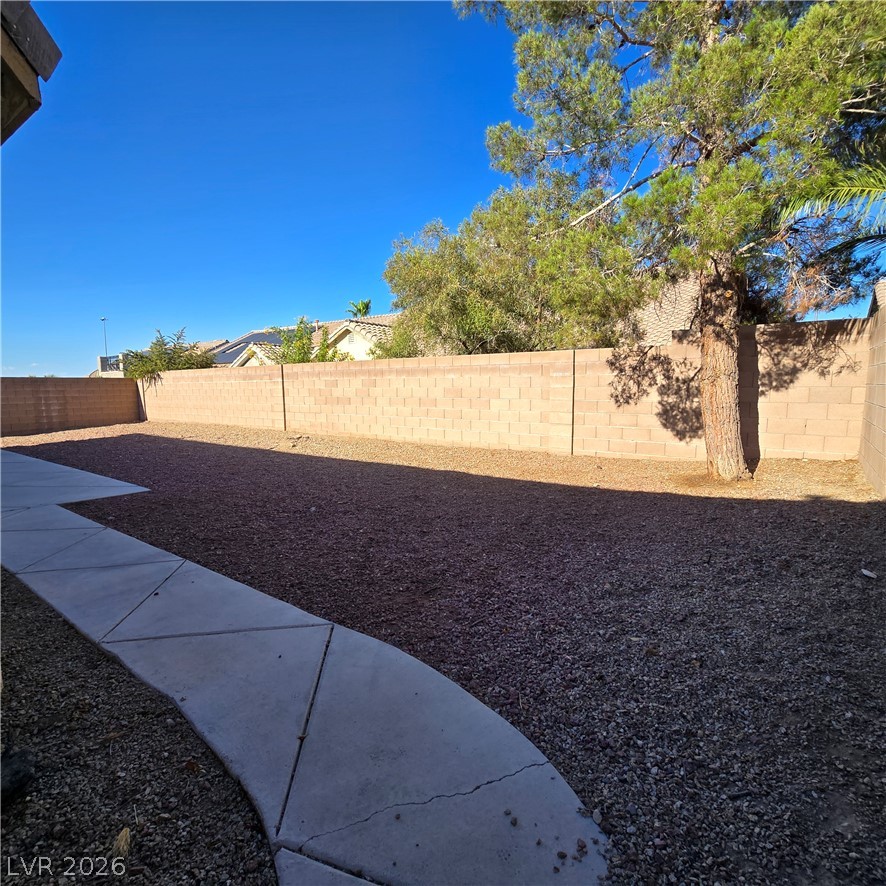 9234 Kingston Road Henderson, NV 89074 - Photo 5 of 38 A spacious backyard awaits, featuring a clean gravel landscape and a substantial block fence.