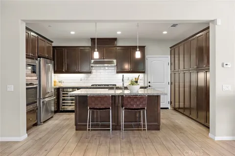 a kitchen with stainless steel appliances a dining table chairs refrigerator and microwave