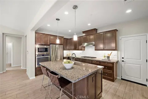 a kitchen with a stove a refrigerator and a wooden floor