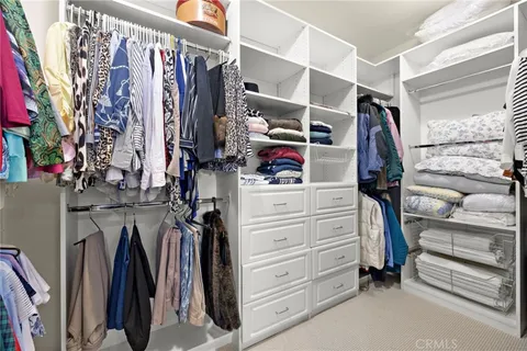 a view of walk in closet with clothes and shoes