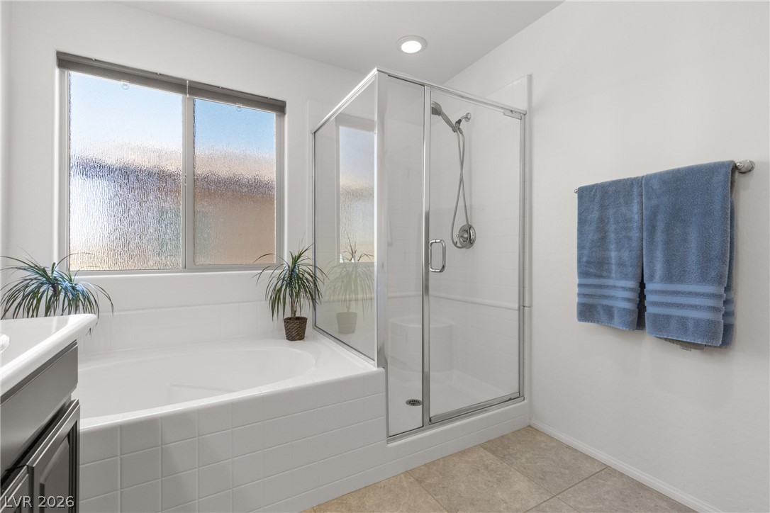 891 Earth Luster Road Las Vegas, NV 89178 - Photo 16 of 48 A spacious bathroom offers a tiled soaking tub, a separate glass-enclosed shower, and ample natural light.