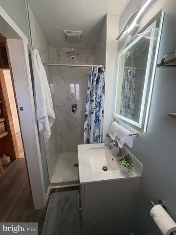 a bathroom with a sink and mirror with bathtub